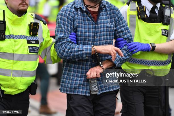 Police officers detain and escort away a climate activist from the Extinction Rebellion group blocking the road at London Bridge in central London on...