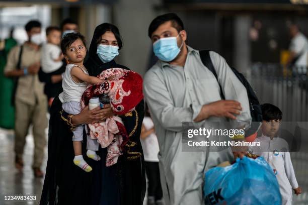 Evacuees who fled Afghanistan walk through the terminal to board buses that will take them to a processing center, at Dulles International Airport on...