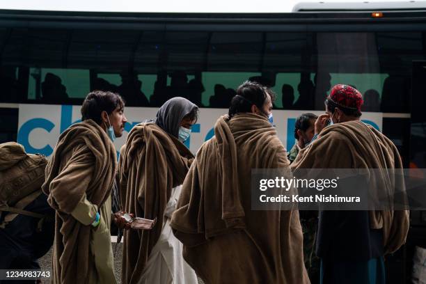 Evacuees who fled Afghanistan walk through the terminal to board buses that will take them to a processing center, at Dulles International Airport on...