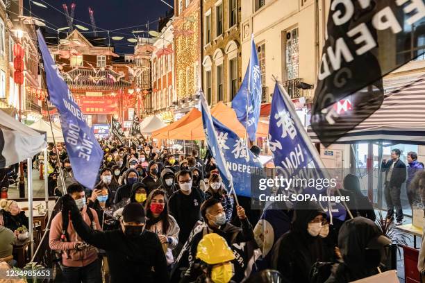 Pro-democracy protesters wave protest flags while marching through China Town in London during the commemoration of the Prince Edward incident, where...