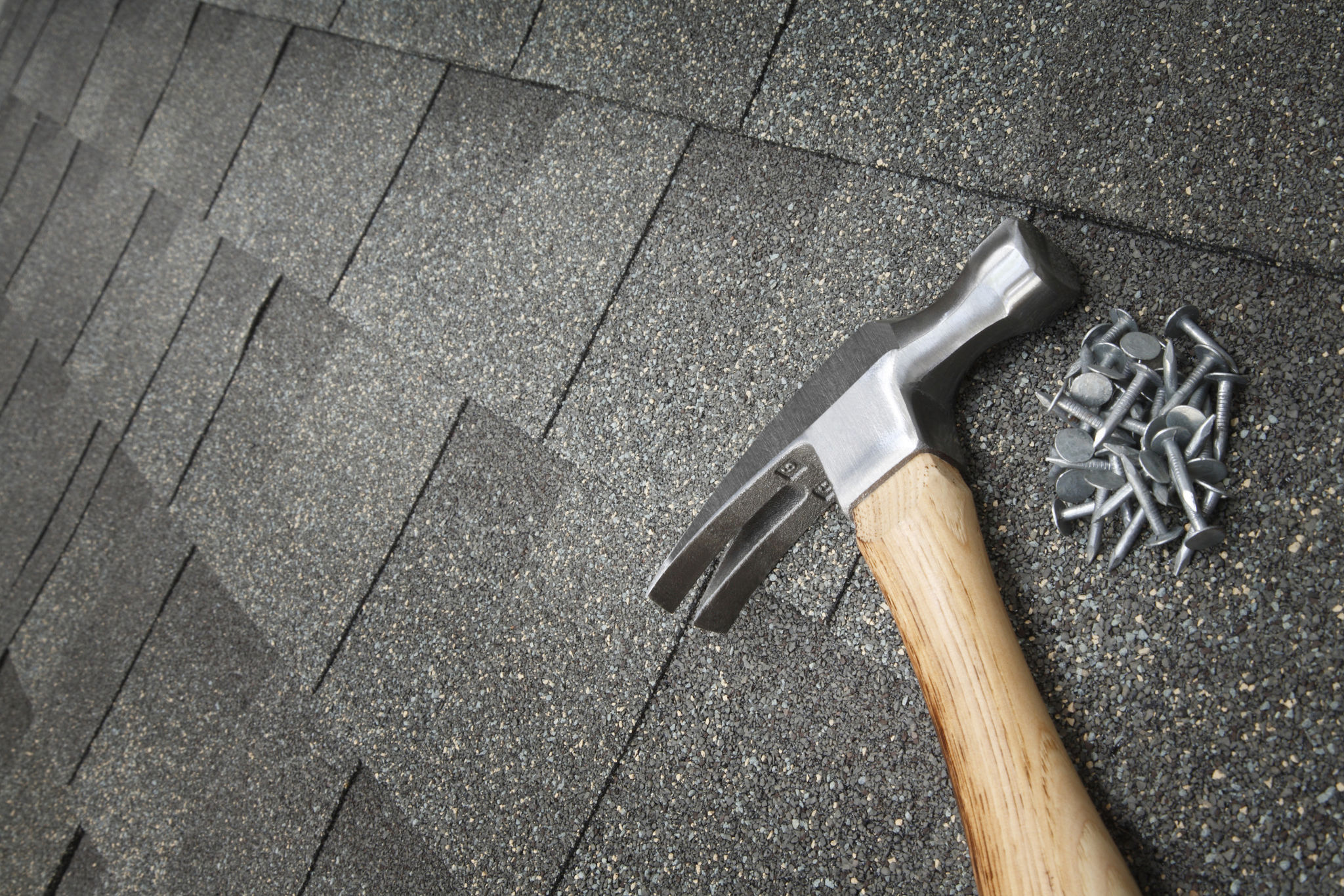 Close-up of a roof repair in progress, with shingles and a hammer on the roof. Roof replacement may be necessary for aging or damaged roofs in Raleigh, NC. Close-up of a roof repair in progress, with shingles and a hammer on the roof. Roof replacement may be necessary for aging or damaged roofs in Raleigh, NC.