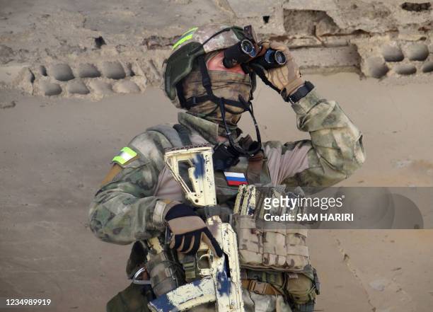 Russian soldier uses a binocular during a patrol in the Syrian district of Daraa al-Balad in Syria's southern province of Daraa, on September 1,...