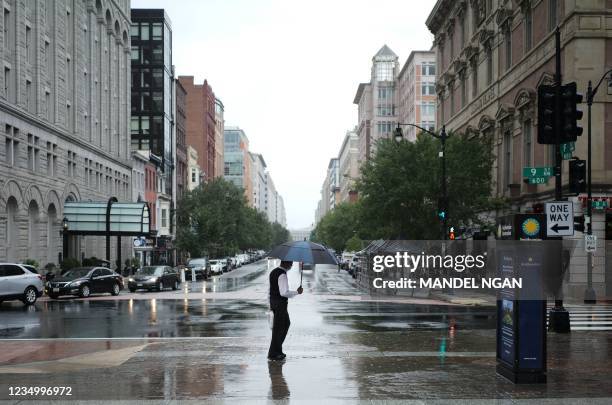 Man holding an umbrella walks on a rainy street in Washington, DC on September 1, 2021 as Idas remnants push into the region. - The remnants of...