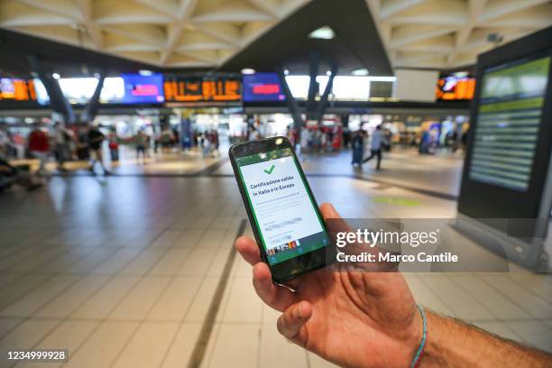 In this photo illustration a hand holding a smartphone with the positive result of the Green Pass verification, in the Naples train station. The...