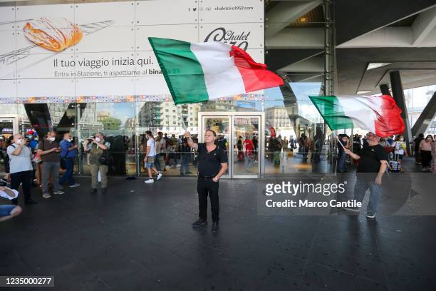 Two men protest by waving the Italian flag, in front of the Naples train station, against the entry into force of the Green Pass, the precautionary...