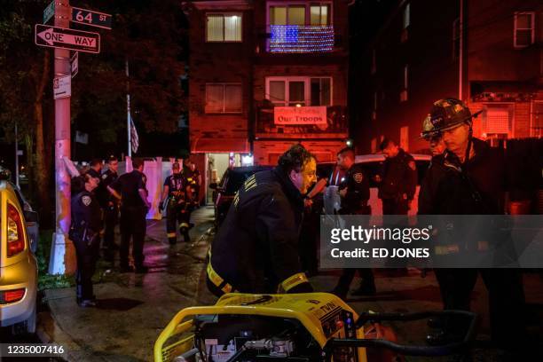 Police officers and rescue workers gather outside a house where a person was trapped in a flooded basement in Queens, New York early on September 2...