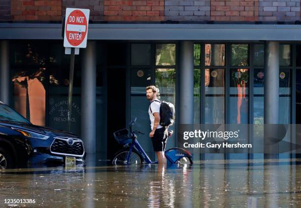 Person stands in a flooded street the morning after the remnants of Hurricane Ida drenched the New York City and New Jersey area on September 2, 2021...