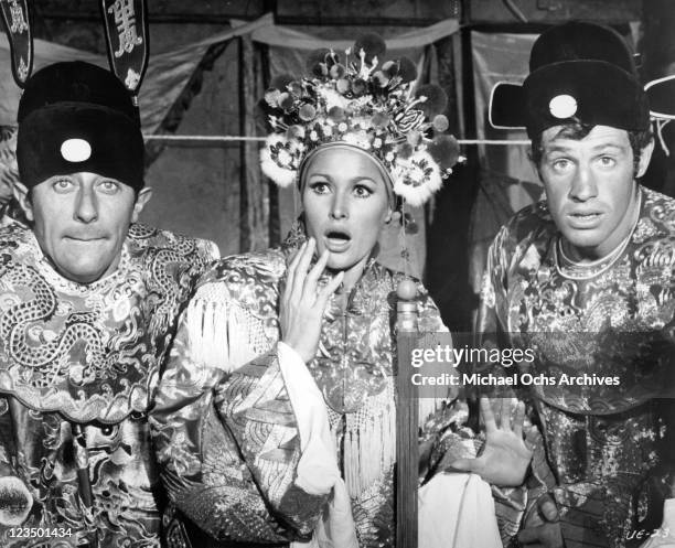 Jean Rochefort, Ursula Andress, and Jean-Paul Belmondo all wearing Chinese mandarin robes in a scene from the film 'Up To His Ears', 1965.