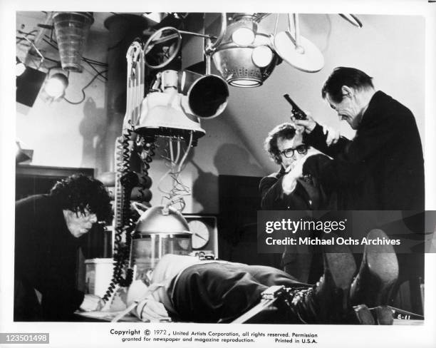 Ref Sanches is standing over a person strapped to a table as Woody Allen and John Carradine wrestles for a gun in a scene from the film 'Every Thing...