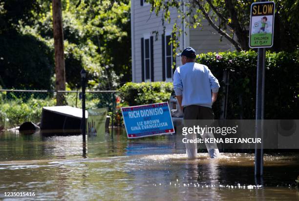Man walks by a flooded street following a night of heavy wind and rain from the remnants of Hurricane Ida on September 02, 2021 in Mamaroneck, New...