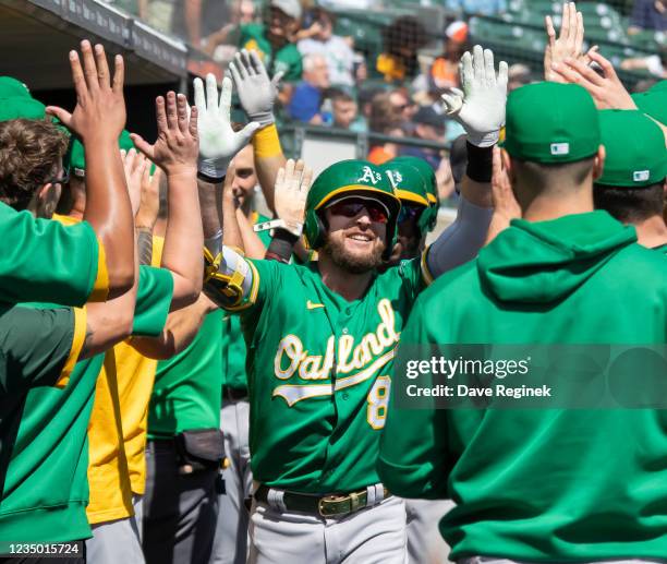 Jed Lowrie of the Oakland Athletics hits a two run home run against the Detroit Tigers in the first inning and celebrates with teammates in the...