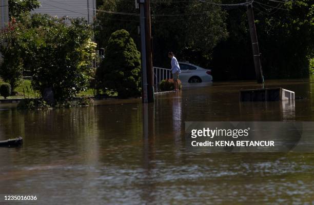 Woman stands on the edge of a sidewalk from a flooded street following a night of heavy wind and rain from the remnants of Hurricane Ida on September...