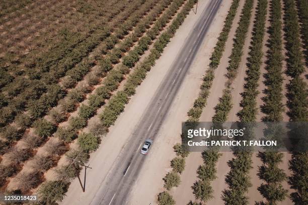 In this aerial image, a car drives on a road with partially repaired potholes past farmland though Tulare County in the Central Valley on August 26,...