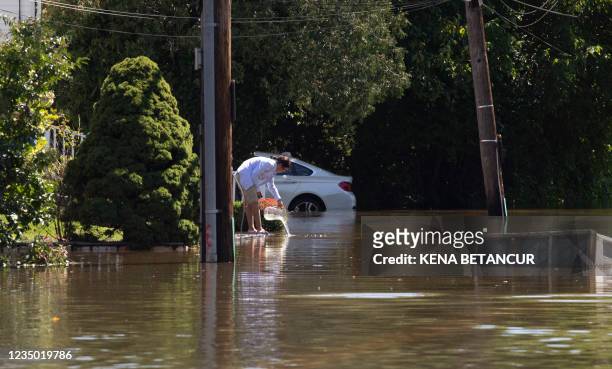 Woman scoops out the water from her front yard after a night of high winds and rain from the remnants of Hurricane Ida on September 2, 2021 in...