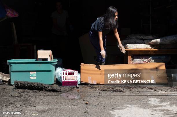Woman removes debris littering a flooded parking after a night of high winds and rain from the remnants of Hurricane Ida on September 2, 2021 in...
