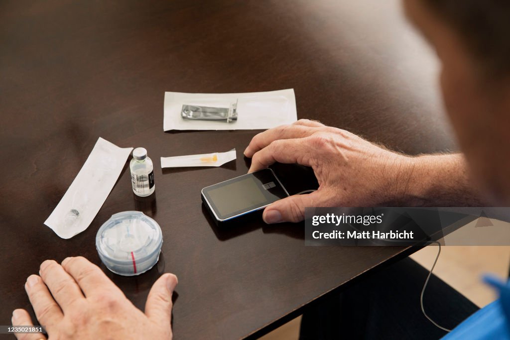 Over the shoulder shot of older man looking at his type-1 diabetes supplies on kitchen table.