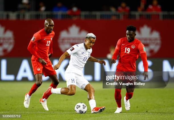 Andy Najar of Honduras dribbles the ball as Atiba Hutchinson and Alphonso Davies of Canada defend during a 2022 World Cup Qualifying match at BMO...