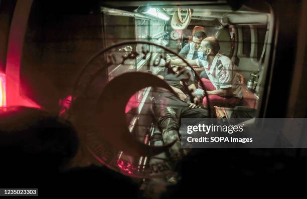 Paramedic treats an injured Palestinian protester inside an ambulance during a night demonstration along the border between the Gaza Strip and Israel...