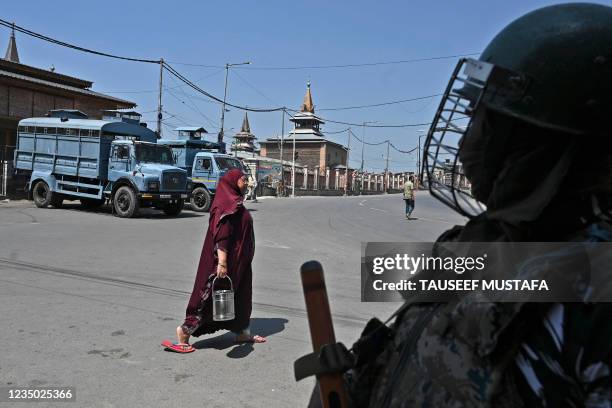 Woman walks past a paramilitary trooper standing on guard near the Jamia Masjid in the downtown area of Srinagar on September 3 as thousands of...