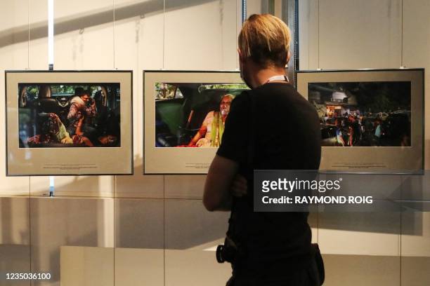 Visitors look at photos displayed at the exhibition "Documenting Indias Greatest Healthcare Crisis" by Indian Reuters photographer Danish Siddiqui...