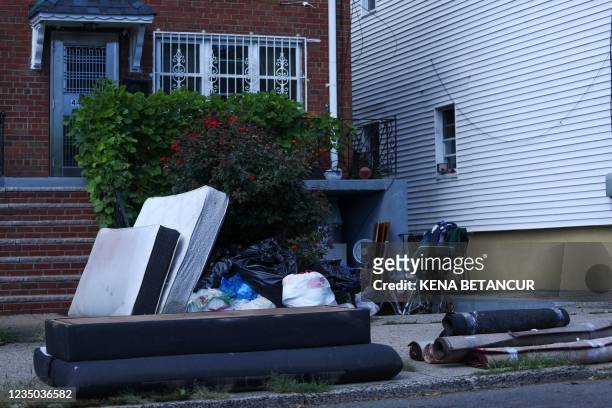 Mattresses and carpets are seen outside a basement next to the building where two adults and a 2-year-old died during flash flooding caused by a...