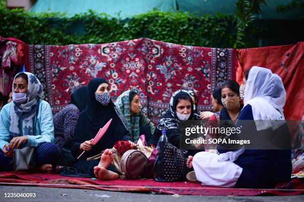 Afghans seen sitting on the ground outside the United Nations High Commissioner for Refugees office during the demonstration. Afghan nationals held a...