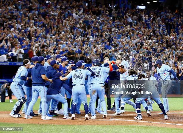 Marcus Semien of the Toronto Blue Jays runs towards home plate where his teammates wait to mob him after hitting a walk-off home run in the ninth...