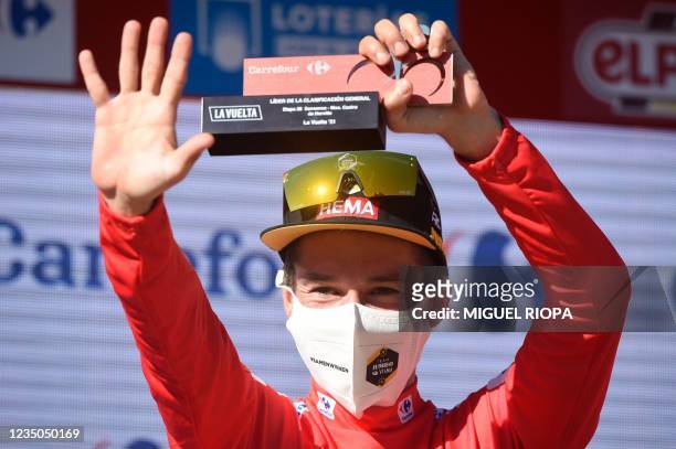 Team Jumbo's Slovenian rider Primoz Roglic celebrates on the podium as he retains the overall leader's red jersey after the 20th stage of the 2021 La...
