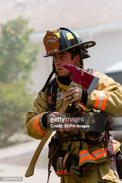 Firefighter grabs an axe as he rushes to a house fire. Firefighters worked to put out and attic fire in a single family home. The cause is still...