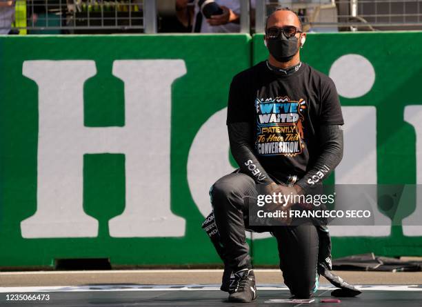 Mercedes' British driver Lewis Hamilton kneels down during F1's 'We Race As One' anti-racism campaign on the grid of the Zandvoort circuit before the...