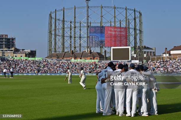 England's openers walk out to begin their second Innings as India's players have a group huddle during play on the fourth day of the fourth cricket...