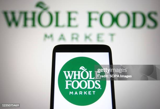 In this photo illustration a Whole Foods Market logo is seen on a smartphone and a pc screen.