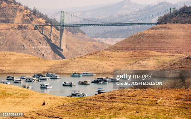 Houseboats sit in a narrow section of water in a depleted Lake Oroville in Oroville, California on September 5, 2021. - Lake Oroville is currently at...