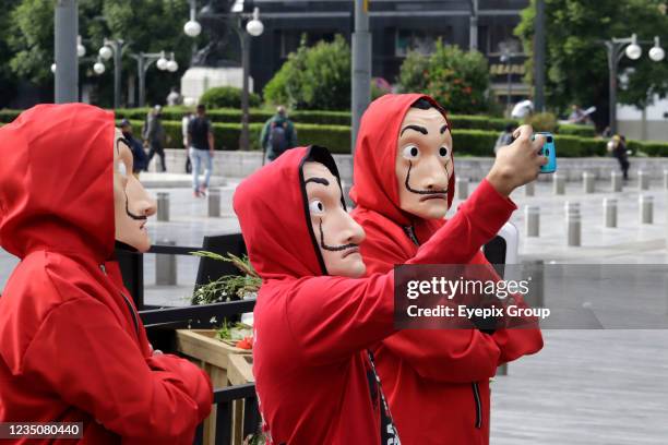 Persons dressed as the characters from the Netflix original series 'La Casa de Papel' take a selfie in a set outside the Palacio de Bellas Artes on...