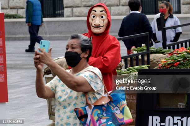 Women takes a selfie with a Person dressed as the characters from the Netflix original series 'La Casa de Papel' put a set outside the Palacio de...