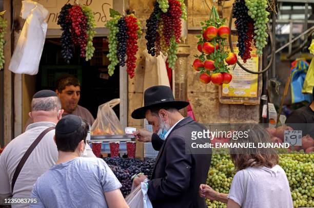 People shop at a market in Jerusalem in preparation for Rosh Hashanah, the Jewish New Year, on September 6, 2021. - Israel said it would relaunch a...
