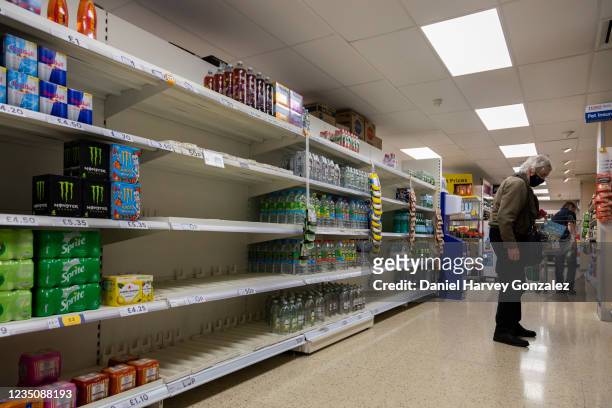 Masked shopper walks the aisles of British supermarket chain Tesco as rows of shelves are left empty amidst nationwide labour shortages on 4th...