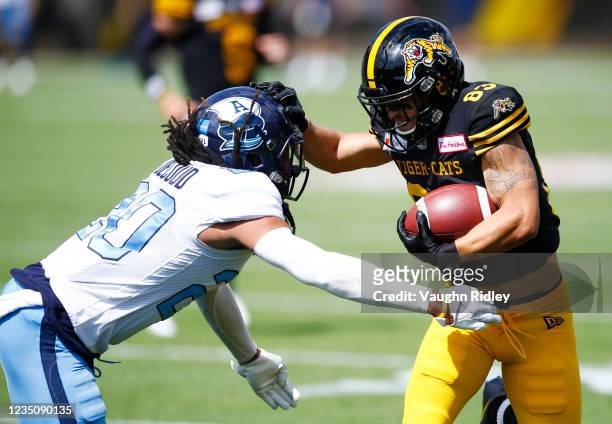 David Ungerer of the Hamilton Tiger-Cats gets past Treston Decoud of the Toronto Argonauts to score a touchdown during a CFL game at Tim Hortons...