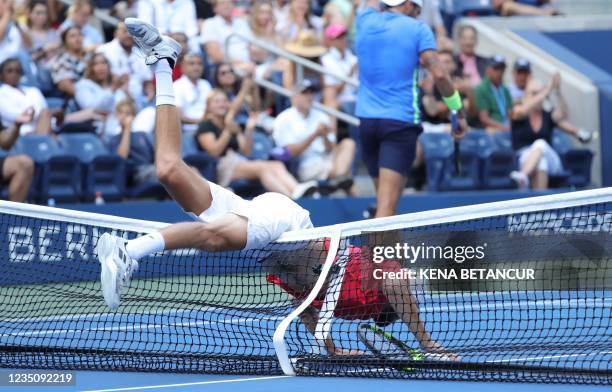 Germany's Oscar Otte falls over the net while playing against Italy's Matteo Berrettini during their 2021 US Open Tennis tournament men's singles...