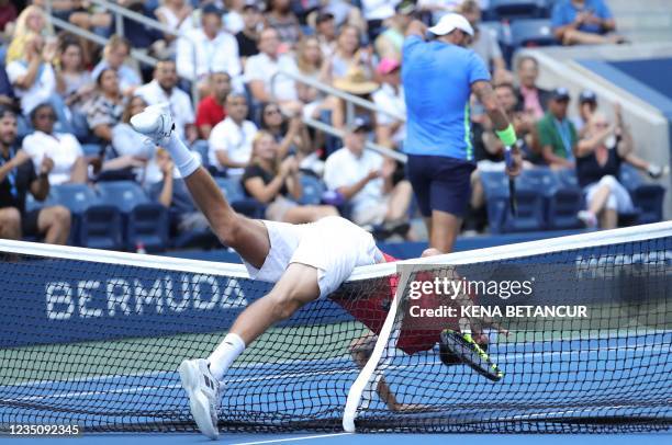 Germany's Oscar Otte falls over the net while playing against Italy's Matteo Berrettini during their 2021 US Open Tennis tournament men's singles...