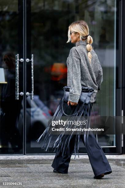 Influencer Gitta Banko wearing a low bubble ponytail hairstyle, a black and white slouchy turtleneck pullover by Airfield, black wide leg pants by...