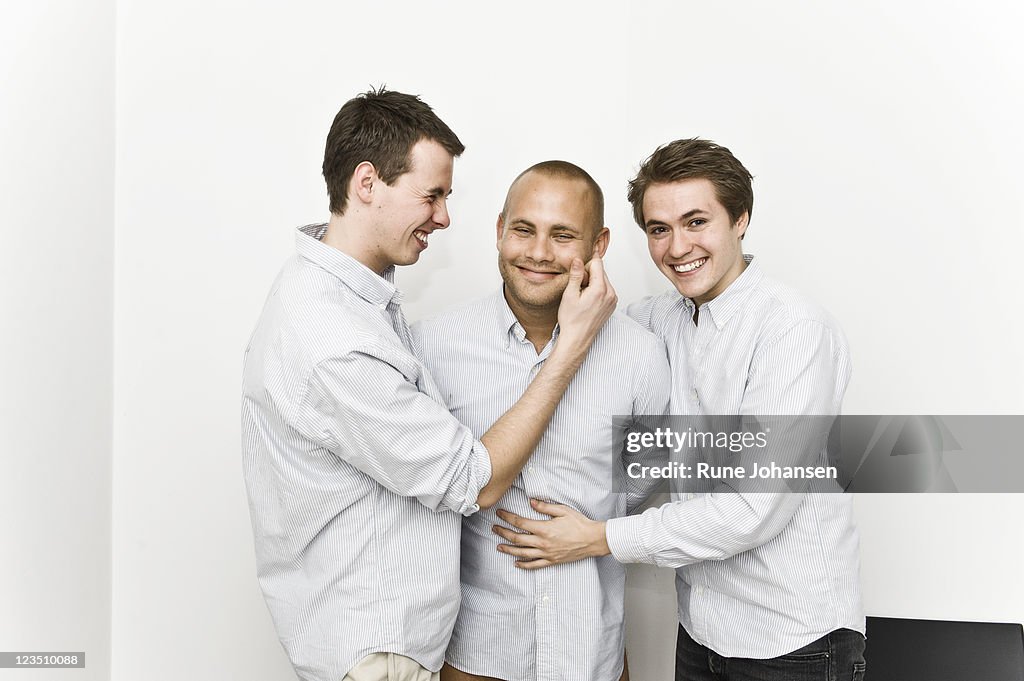 Portrait of young men embracing their fellow member of Secret society on the cheek, Denmark