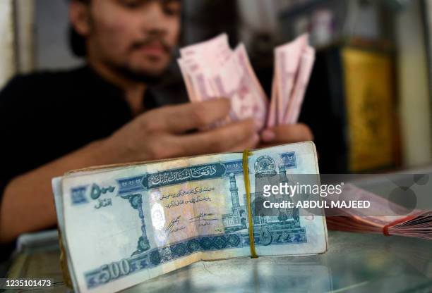 Money changer counts Afghanistan's banknotes afghani in a market in Peshawar on September 7, 2021.