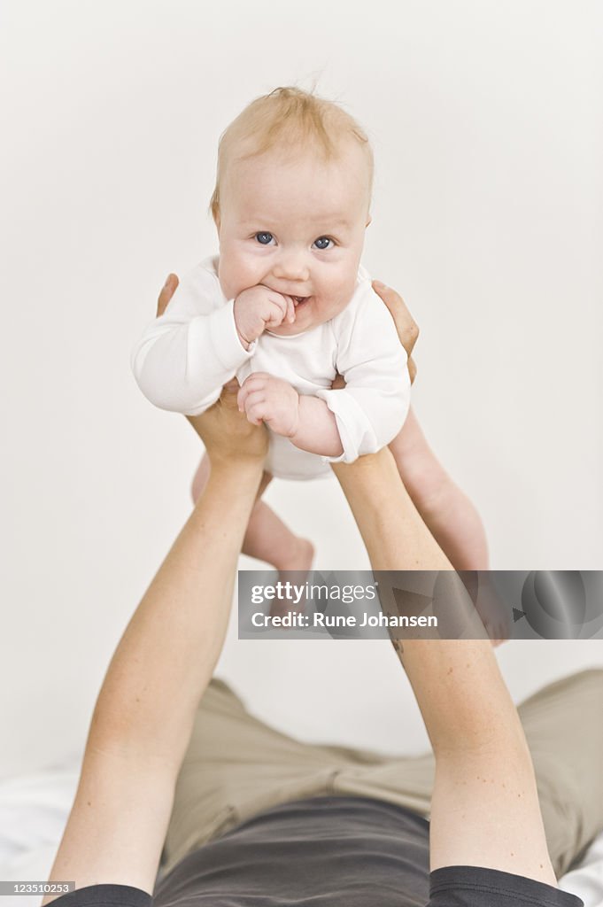 Danish baby being held up by father's arms