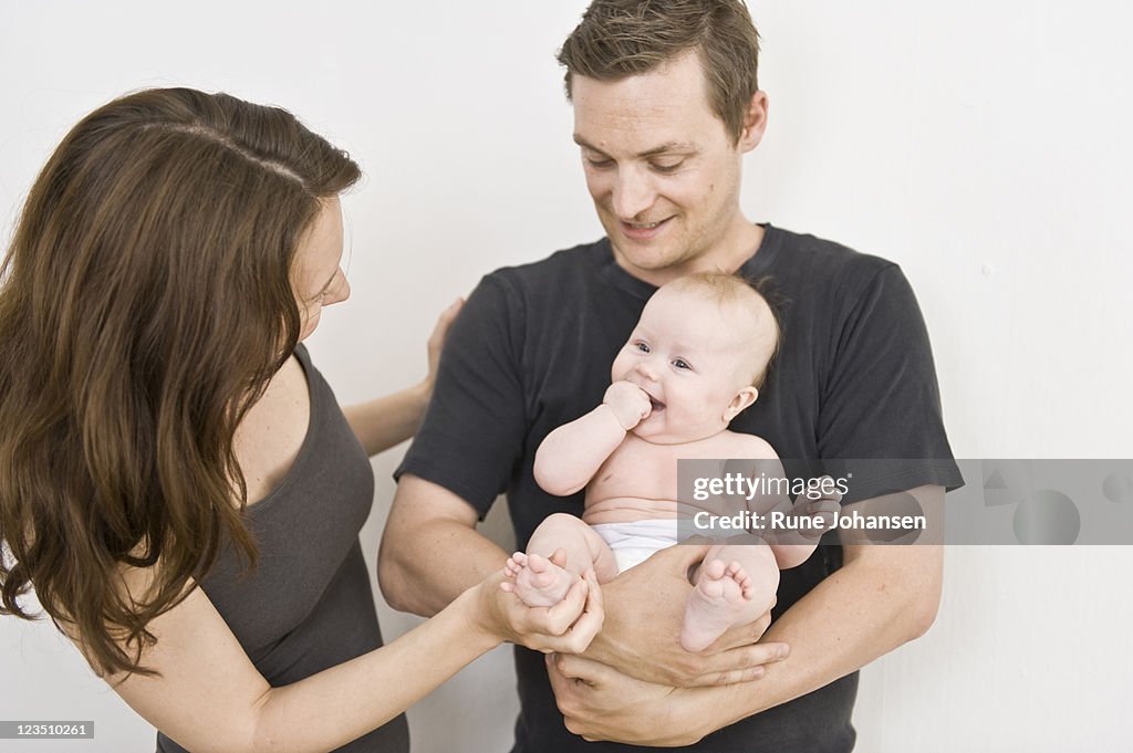 Danish family with father, 31 years old, holding daughter, while mother, 31 years old, looks at her