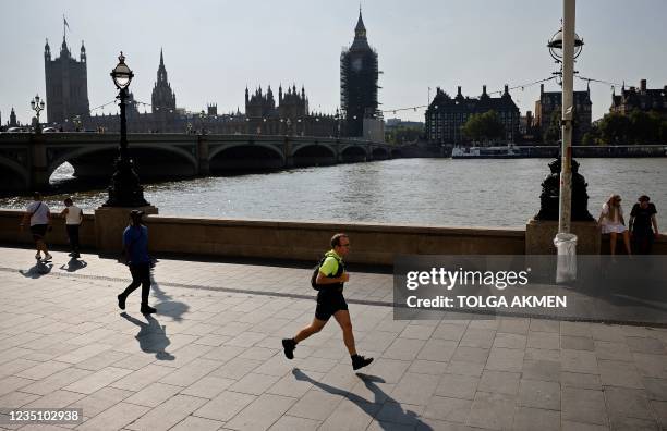 Jogger runs along the south bank of hte River Thames, opposite the Houses of Parliament in London on September 7, 2021. - Breaking an election pledge...