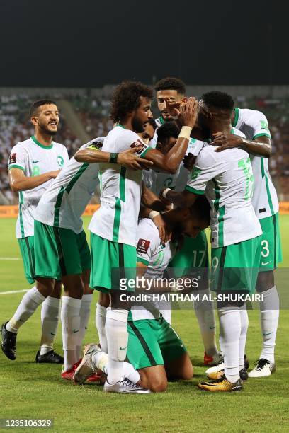 Saudi's players celebrate their opening goal during the 2022 Qatar football World Cup Asian Qualifiers match between Oman and Saudi Arabia, at the...