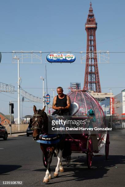 Man drives a horse and carriage up the main strip with the world famous Blackpool Tower in the background as temperatures in the country are expected...