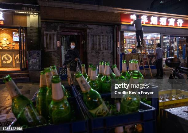 Man carries empty beer bottles as he collects them from a restaurant in a hutong neighborhood on September 8, 2021 in Beijing, China. While cases...