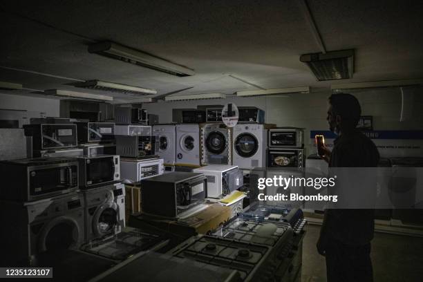 Store owner uses a mobile phone torchlight in an electrical goods shop during a power cut in Beirut, Lebanon, on Tuesday, Sept. 7, 2021. Egypt agreed...